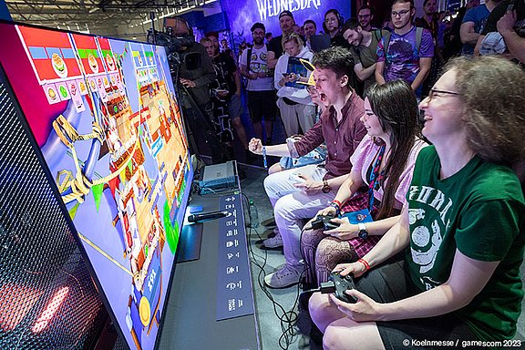 Gruppen von jungen Menschen spielen Videospiele bei der Koelnmesse, voller Energie und Begeisterung, Gaming-Event.